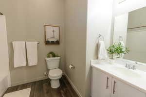 Full bathroom with vanity, baseboards, toilet, and wood finished floors