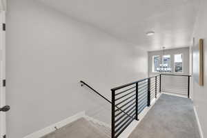 Stairway with a textured ceiling, baseboards, a chandelier, and carpet