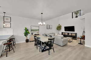 Dining area with a textured ceiling, baseboards, a chandelier, and light wood-type flooring