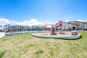 Community play area featuring fence, a yard, a residential view, and a tennis court