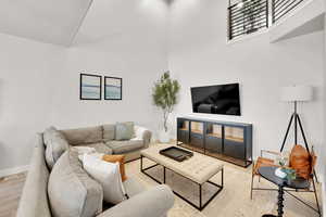 Living room with baseboards, a high ceiling, wood finished floors, and visible vents