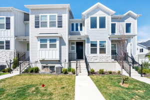 Townhome / multi-family property with stone siding, cooling unit, and a front yard