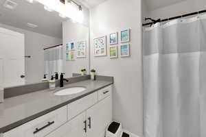 Full bath with visible vents, curtained shower, and vanity