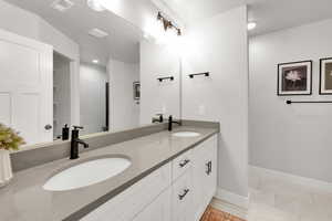 Bathroom featuring a sink, baseboards, double vanity, and visible vents