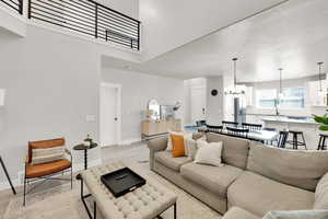 Living room with baseboards, light wood-style flooring, a high ceiling, and a chandelier