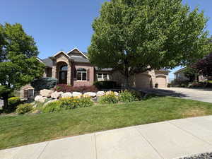 View of front of home with stone siding, a front yard, brick siding, and asphalt driveway
