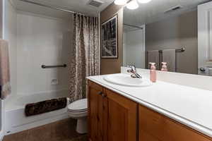 Full bathroom featuring tile patterned flooring, shower / bath combo, toilet, and visible vents
