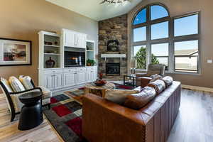 Living room featuring light wood-style floors, baseboards, a fireplace, and high vaulted ceiling