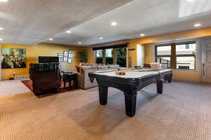Recreation room featuring recessed lighting, a textured ceiling, light colored carpet, and visible vents