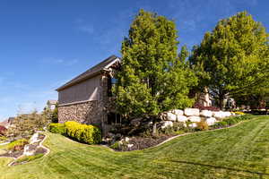 View of property exterior with a yard and stone siding
