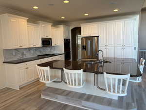 Kitchen featuring a kitchen breakfast bar, white cabinets, appliances with stainless steel finishes, recessed lighting, and arched walkways