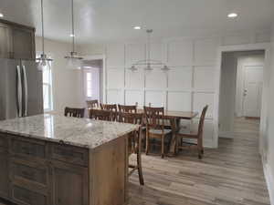 Kitchen with a decorative wall, light wood-style flooring, a center island, recessed lighting, and pendant lighting