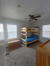 Carpeted bedroom with a ceiling fan and baseboards