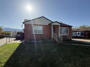Bungalow-style home featuring fence, concrete driveway, a front lawn, and brick siding