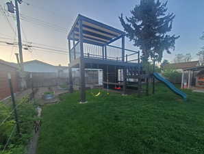 View of play area with a fenced backyard, a yard, and a deck