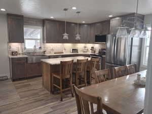 Kitchen featuring light wood-style floors, appliances with stainless steel finishes, a sink, and tasteful backsplash