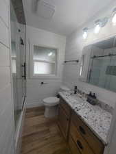 Bathroom with toilet, a textured ceiling, wood finished floors, and a stall shower