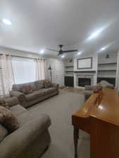 Living room with a fireplace, a ceiling fan, and wood finished floors