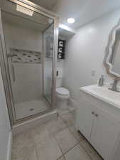 Bathroom with vanity, toilet, tile patterned floors, baseboards, and a shower stall