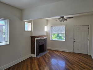 Unfurnished living room with baseboards, a fireplace, a wealth of natural light, and hardwood / wood-style flooring