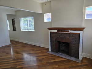 Unfurnished living room with baseboards, a fireplace, wood finished floors, and a wealth of natural light