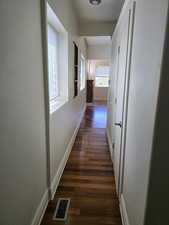 Hallway with visible vents, baseboards, and dark wood-type flooring