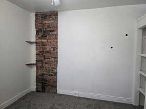 Unfurnished room featuring dark colored carpet, a ceiling fan, and baseboards