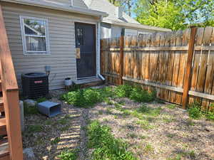 View of yard with central air condition unit and fence