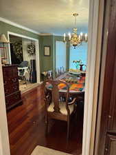 Dining space with a notable chandelier, crown molding, and wood finished floors