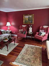 Living area with baseboards, crown molding, and wood finished floors