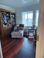Living area featuring crown molding, baseboards, and wood finished floors