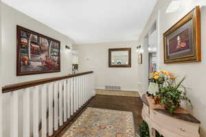 Hall with baseboards, visible vents, and dark wood-style floors