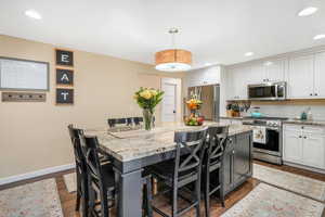 Kitchen featuring baseboards, a kitchen bar, a center island, appliances with stainless steel finishes, and backsplash
