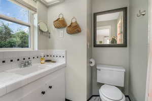 Bathroom with vanity, backsplash, and toilet