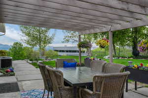 View of patio featuring cooling unit, a mountain view, a fenced backyard, a pergola, and outdoor dining space