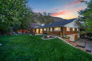 Back of house at dusk with fence, a patio, an outdoor hangout area, and a lawn