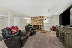 Living room with carpet flooring, visible vents, wainscoting, and a fireplace