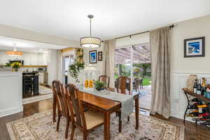 Dining space featuring wainscoting, dark wood-style flooring, and a decorative wall