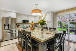 Kitchen featuring a kitchen island, appliances with stainless steel finishes, a breakfast bar, and dark wood-type flooring