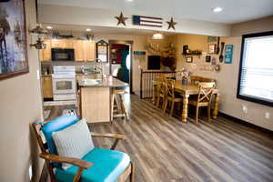 Kitchen featuring light brown cabinetry, black microwave, a sink, wood finished floors, and white electric range