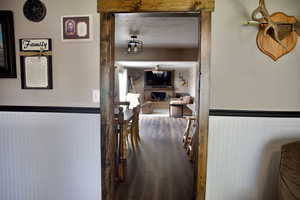 Hallway with wood finished floors and a wainscoted wall