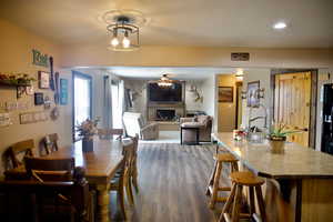 Dining area with a brick fireplace, recessed lighting, ceiling fan, and dark wood finished floors