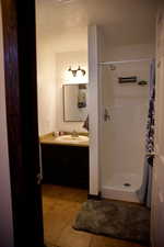 Full bathroom featuring vanity, tile patterned flooring, a shower stall, and a textured ceiling