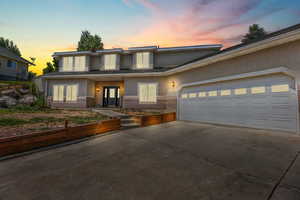 View of front facade featuring brick siding, a garage, stucco siding, concrete driveway, and french doors