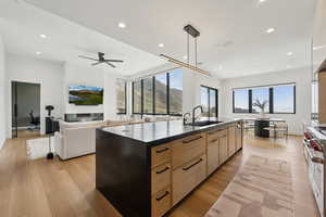 Kitchen featuring light brown cabinetry, dark countertops, a sink, double oven range, and modern cabinets