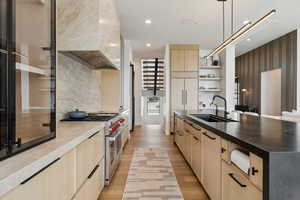 Kitchen featuring light brown cabinetry, double oven range, custom exhaust hood, and a sink