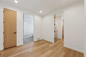 Spare room with light wood-style floors, baseboards, recessed lighting, and visible vents