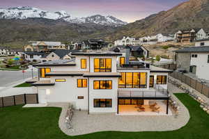 Back of property at dusk featuring a residential view, a fenced backyard, a patio area, a balcony, and a yard