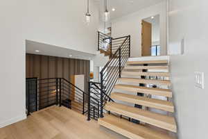 Staircase featuring baseboards, a towering ceiling, wood finished floors, and visible vents