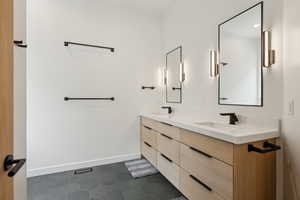 Full bathroom with double vanity, baseboards, a sink, and tile patterned floors